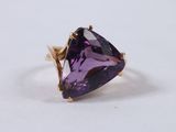 a close up of a purple stone ring on a white surface
