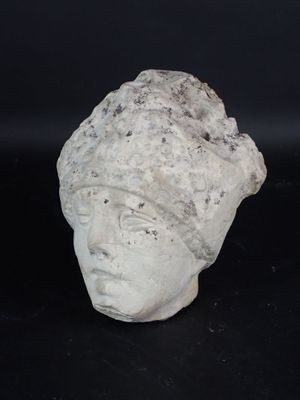 une tête de femme en pierre coiffée d'un chapeau