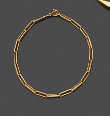 un bracelet en or et une paire de ciseaux posés sur une table
