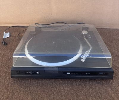 une platine posée par terre à côté d'une télécommande