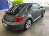the back of a gray volkswagen beetle parked in a garage