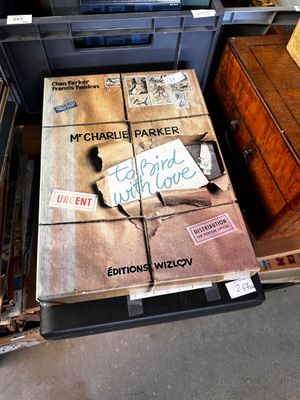 une grande boîte sur laquelle est accrochée une pancarte, posée par terre