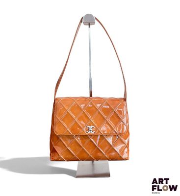 un sac Chanel orange avec une poignée en métal sur fond blanc