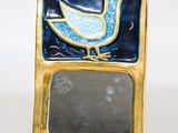 un petit miroir orné d'un oiseau, posé sur un socle