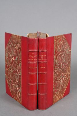 two red books with gold trims are open on a gray surface
