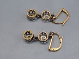 a pair of gold earrings with black and white stones on them