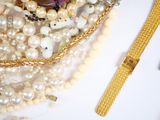 a bunch of pearls and a gold watch on a table