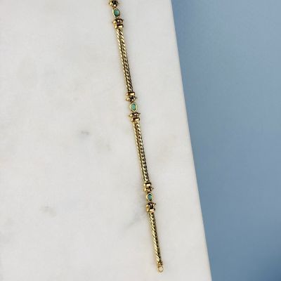 collier plaqué or orné de perles de verre vertes sur un fond de marbre blanc