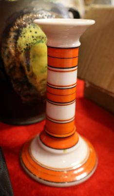 un bougeoir rayé orange et blanc posé sur une table rouge