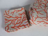 two pieces of cloth with orange designs on them on a white surface