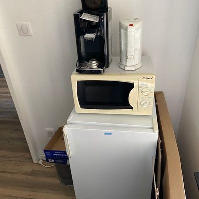 un micro-ondes posé sur un petit réfrigérateur dans une pièce