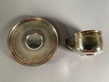 silver plated cup and saucer on a white surface
