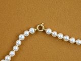 a close up of a pearl necklace on a brown surface