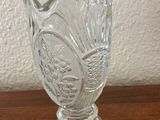 a glass vase on a table with a white wall in the background