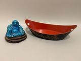 un bol rouge et une statue de Bouddha bleue, placés l'un à côté de l'autre