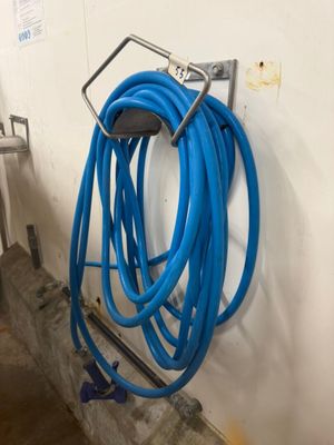 un tuyau bleu fixé au mur à côté d'une échelle