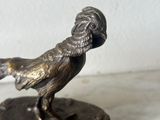bronze figurine of a bird on a base on a marble surface