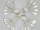 six fourchettes et cuillères disposées en cercle sur une surface blanche