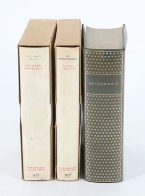 trois livres sont empilés sur une surface blanche