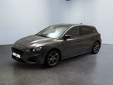La voiture grise est garée dans une grande pièce au sol noir.