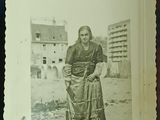 an old black and white photo of a woman standing in front of a building