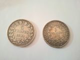 two silver coins sitting side by side on a white surface