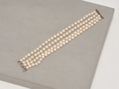 un gros plan d'un bracelet de perles blanches posé sur une surface grise