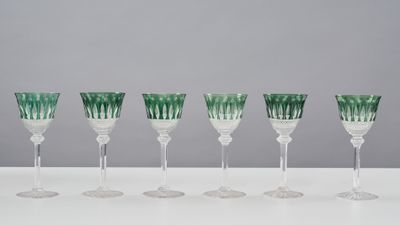 six green and white wine glasses lined up on a table