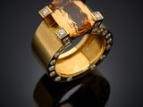 a close up of a ring with an orange topaz stone and diamonds