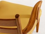 the back of a yellow chair with a wooden frame and yellow cushion