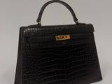 a black crocodile skin handbag on a white background