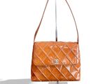 un sac Chanel orange avec une poignée en métal sur fond blanc
