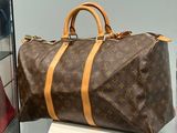 a brown and tan louis vuitton bag sitting on a white pedestal