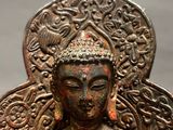 statue of a buddha sitting on a chair with a red and gold paint on it ' s body
