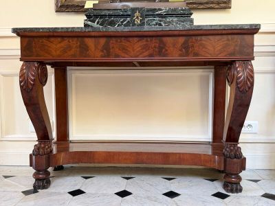 une table au plateau en marbre dans une pièce où est accroché un tableau au mur