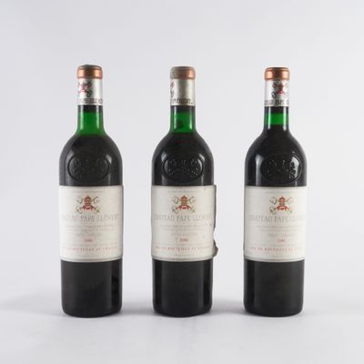 trois bouteilles de vin rouge sont posées côte à côte sur une surface blanche