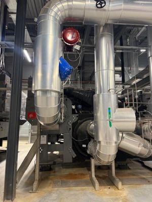pipes and valves in a large industrial building with a clock on the wall