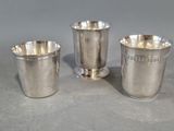 trois tasses en argent posées sur une table, l'une à côté de l'autre