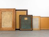 several framed and unframed art pieces are sitting on the floor