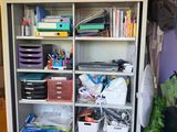 a bookcase filled with lots of office supplies in a room