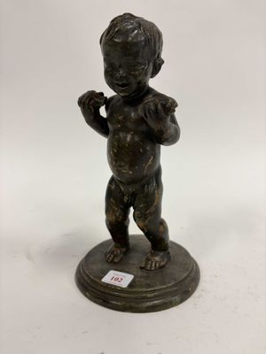une figurine antique en bronze représentant un garçon tenant un gant de baseball