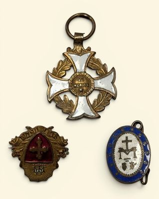 three medals are displayed on a white surface, including a cross, a medal, and a medal