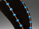 a blue and orange beaded necklace on a black mannequin
