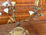 a brass candle holder with flowers in it on a wooden table