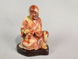 une petite figurine représentant un moine assis sur un rocher