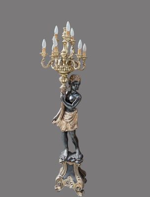 statue of a woman holding a candelab with a chandelier in the background