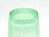 a green glass vase with water in it on a white surface