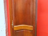 une grande armoire en bois devant un mur rouge