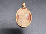 un gros plan d'un pendentif plaqué or représentant le profil d'une femme