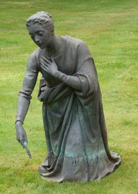une statue représentant une femme assise dans l'herbe